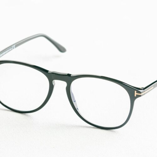 Minimalist close-up of fashionable black eyeglasses on a white surface.