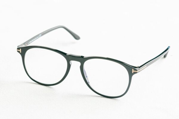 Minimalist close-up of fashionable black eyeglasses on a white surface.