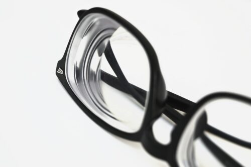 Photo by Marta Branco Modern black frame eyeglasses close-up on white surface, showcasing stylish eyewear design.