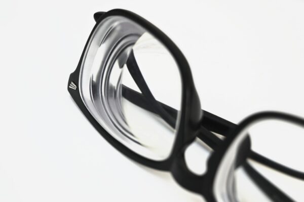 Modern black frame eyeglasses close-up on white surface, showcasing stylish eyewear design.